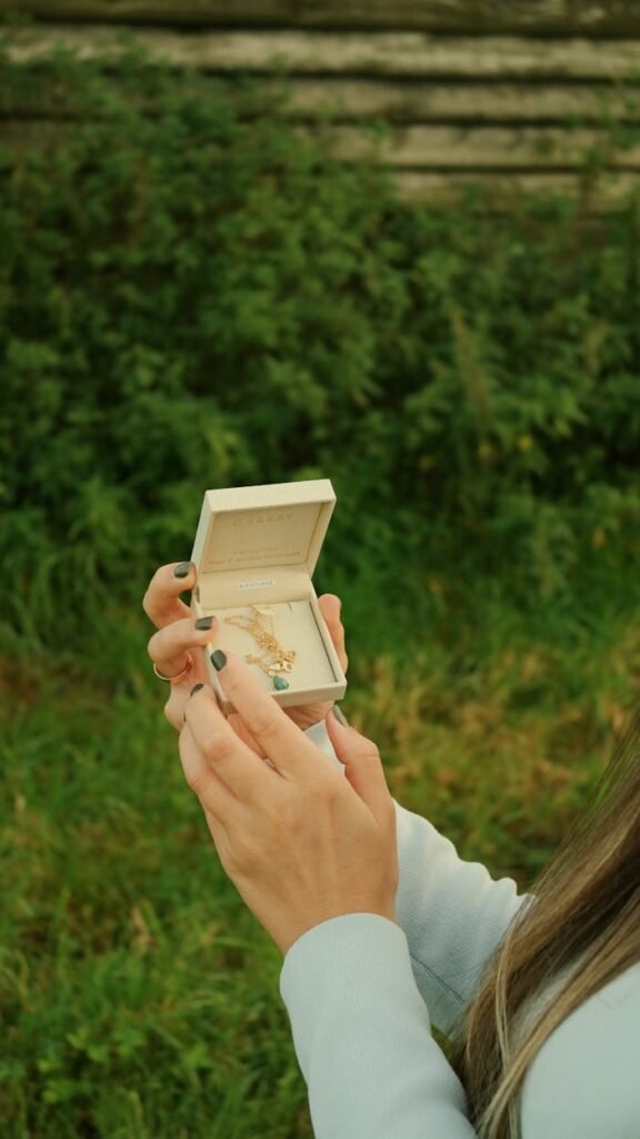pexels photo 28750720 A woman's hands open a jewelry box displaying a necklace against a natural background.